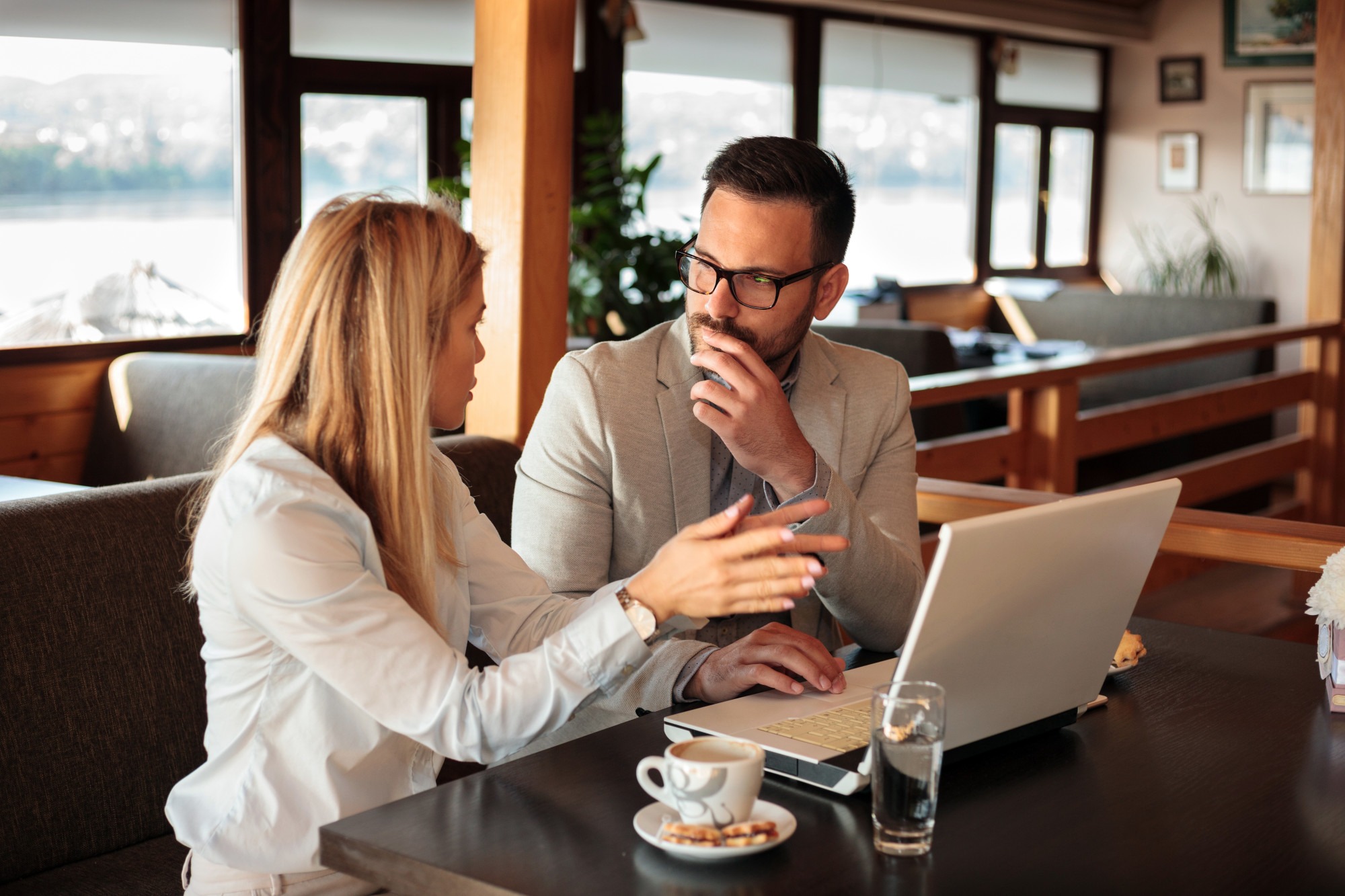 Two young male and female business partners having a meeting in a restaurant. Discussing and planning insurance needs.