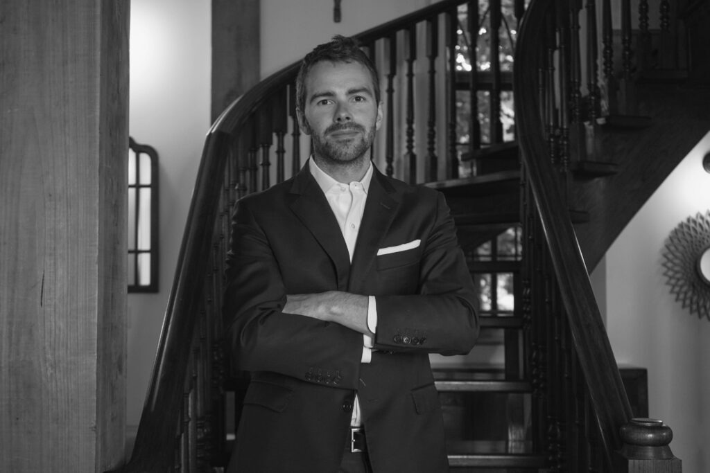 James Inwood, Oakville insurance broker wearing a suit near a staircase with his arms crossed