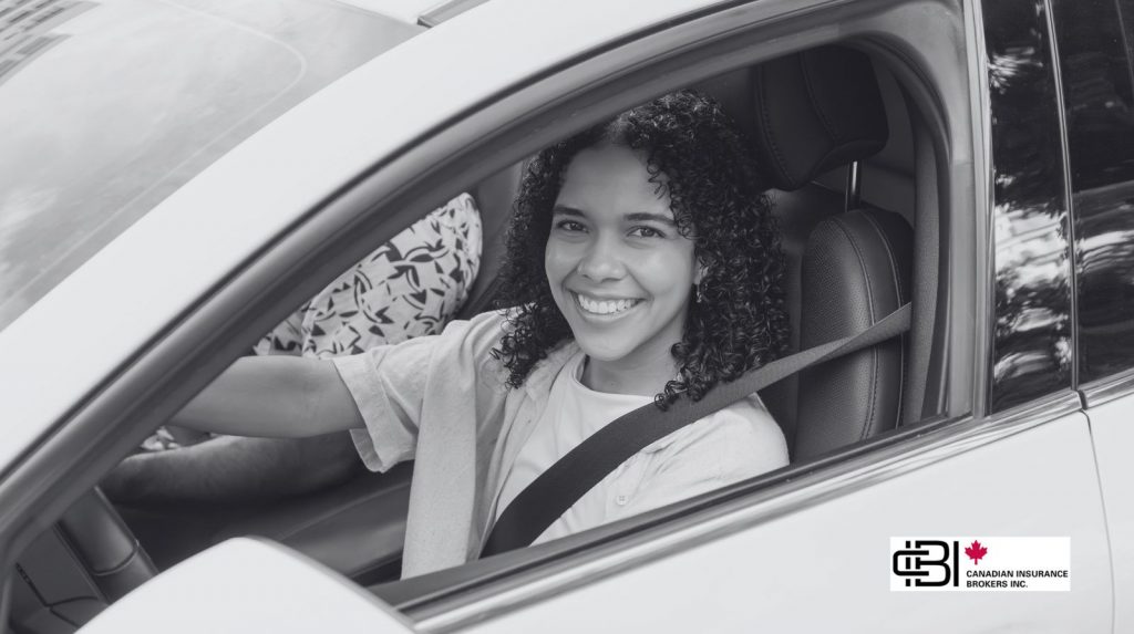 Young driver smiling inside a car wearing a seatbelt, representing G2 insurance for new drivers and safe driving habits.
