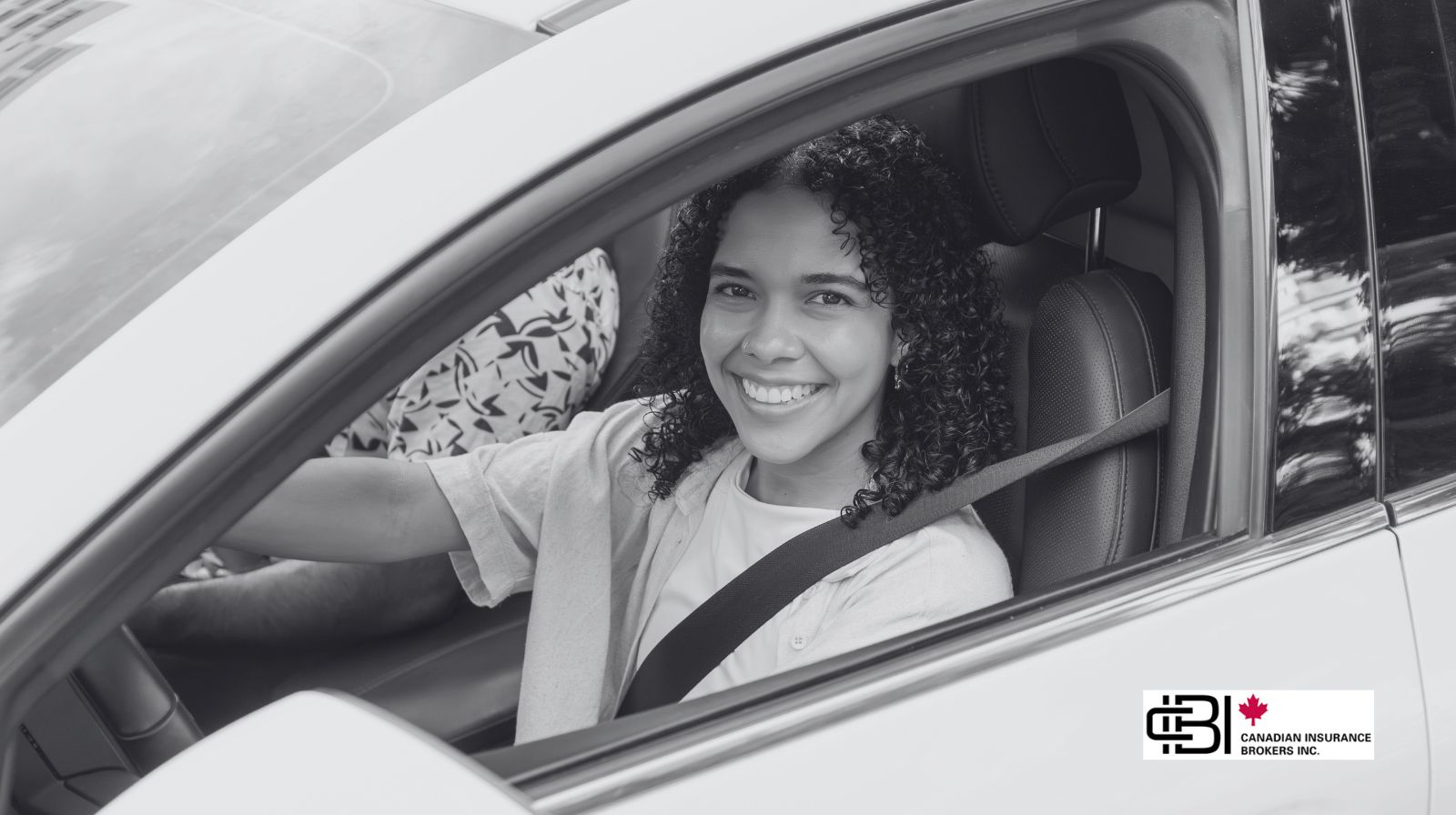 Young driver smiling inside a car wearing a seatbelt, representing G2 insurance for new drivers and safe driving habits.