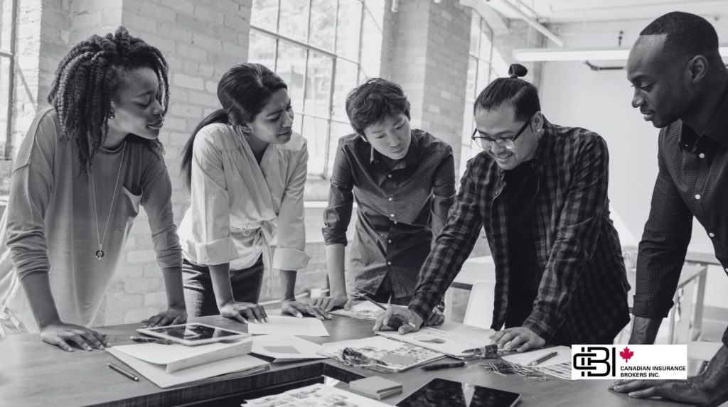 Diverse team collaborating at a table with documents and devices, illustrating startup insurance for business operations and team-based projects.