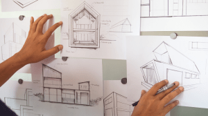 Architectural design sketches and building plans displayed on a wall during the early design stage of an architectural project.