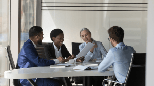 Staffing agency professionals reviewing hiring documents and candidate details during a client meeting in Oakville