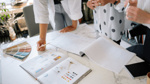 Design professionals reviewing layouts, colour palettes, and creative plans at a worktable.