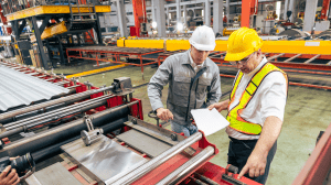 Mechanical engineers inspecting industrial equipment and technical drawings inside a manufacturing facility in Ontario.