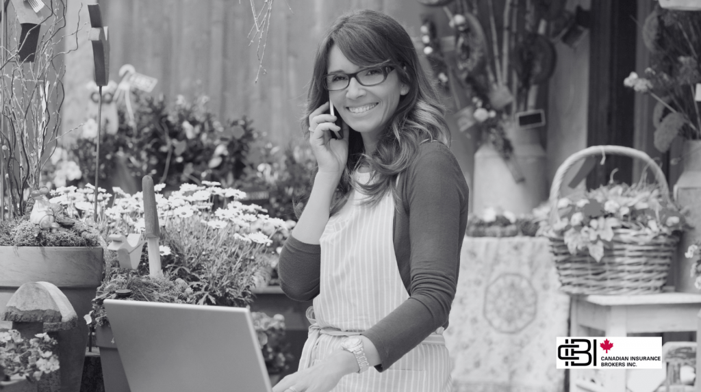 Local florist speaking on the phone discuss about small business insurance in oakville while working on a laptop in her flower shop