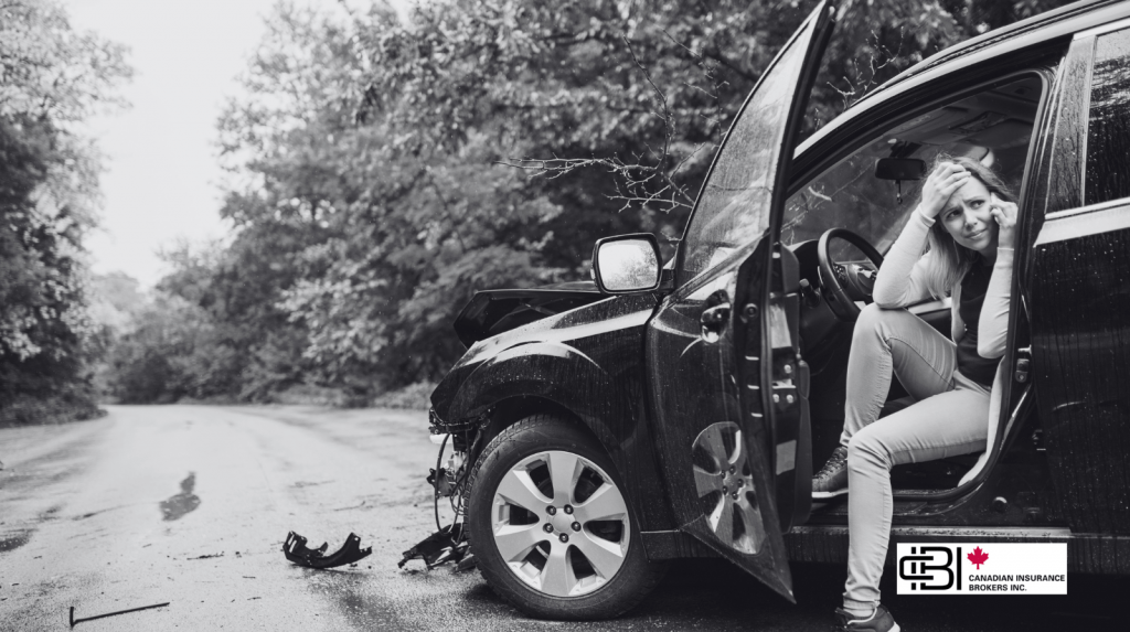 Driver sitting beside a damaged vehicle after a collision, highlighting the importance of comprehensive car insurance in Oakville